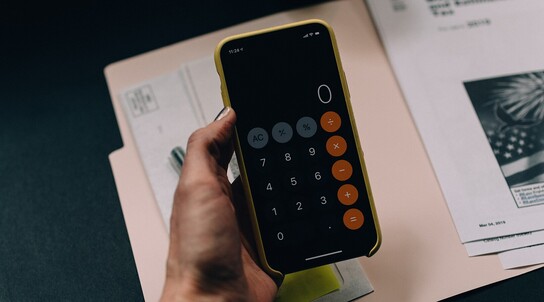 Hand hält Smartphone mit geöffnetem Taschenrechner-App