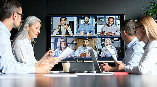 Global corporate video call in meeting room with diverse multiethnic people.