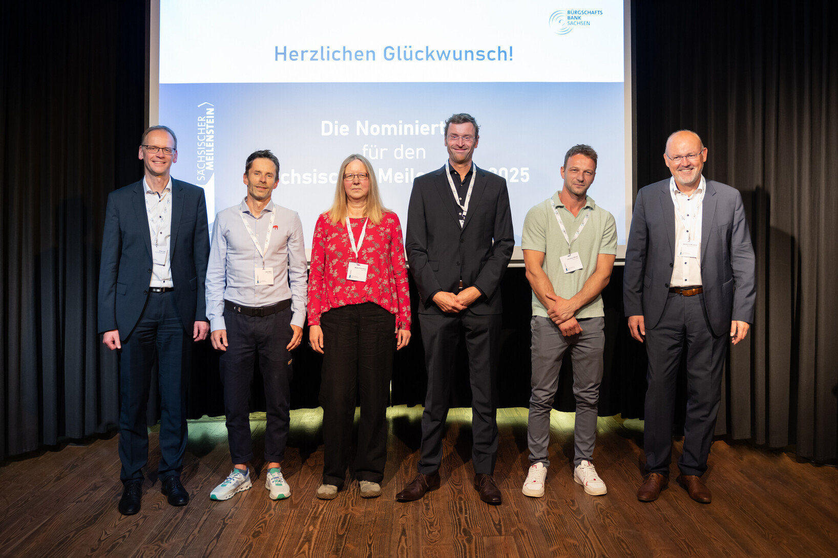 Nominierte des Sächsischen Meilensteins 2025 stehen nebeneinander auf einer Holzbühne