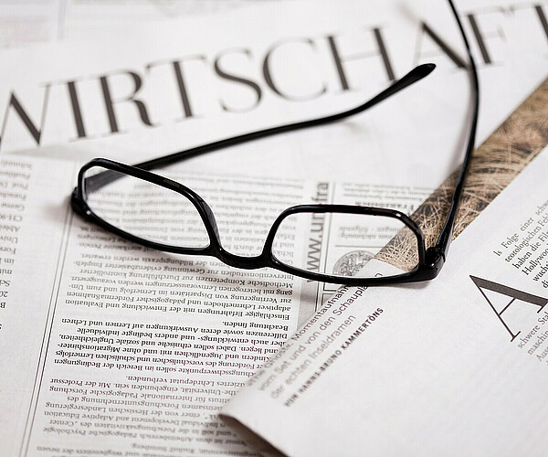Brille liegt auf Wirtschaftszeitungen