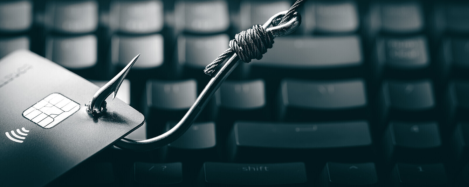 Phishing trifft auch Unternehmen | © Adobe Stock Fischhaken zieht Kreditkarte über Tastatur
