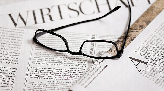 Brille auf Wirtschaftszeitungen