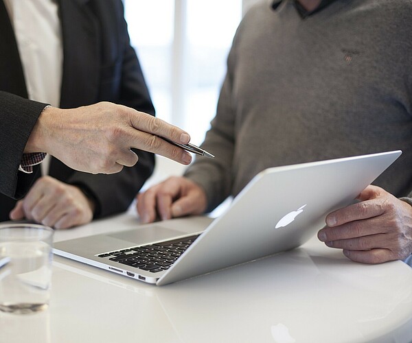 zwei Personen unterhalten sich während sie auf ein Laptop schauen