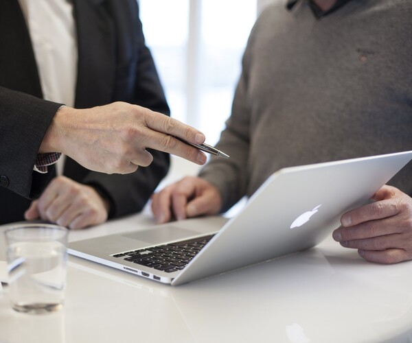 zwei Personen unterhalten sich während sie auf ein Laptop schauen