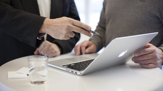 zwei Personen unterhalten sich während sie auf ein Laptop schauen