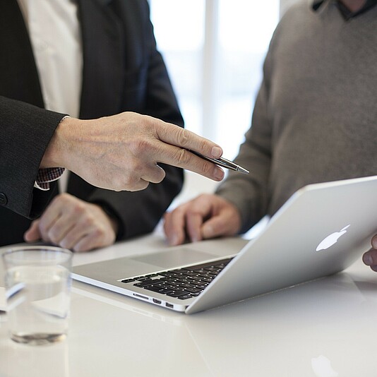 zwei Personen unterhalten sich während sie auf ein Laptop schauen