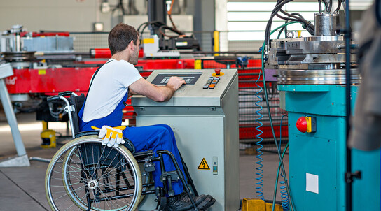 disabled worker in wheelchair in factory and his colleague