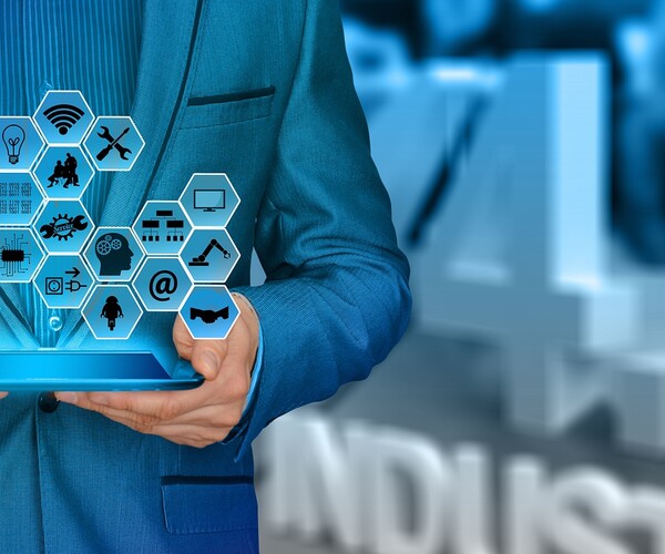 Mann hält Tablet das Logos projiziert in der Hand und steht vor einem 4.0 Industrie Logo