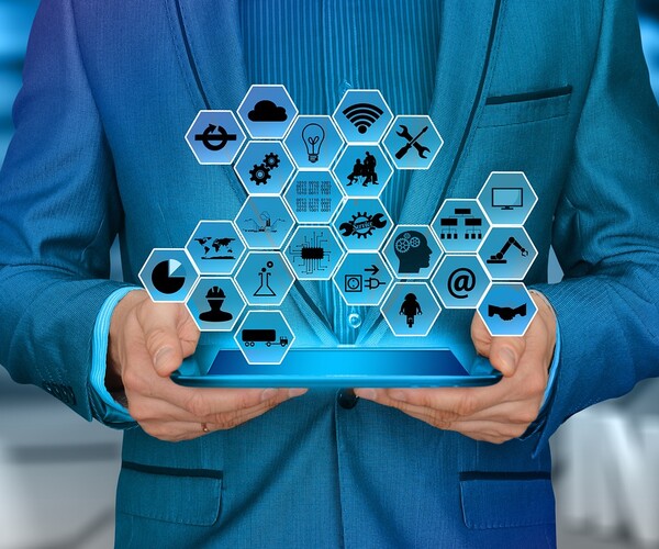 Mann hält Tablet das Logos projiziert in der Hand und steht vor einem 4.0 Industrie Logo