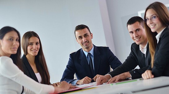 Gruppe von Büroarbeitern lächelt während eines Meetings in die Kamera