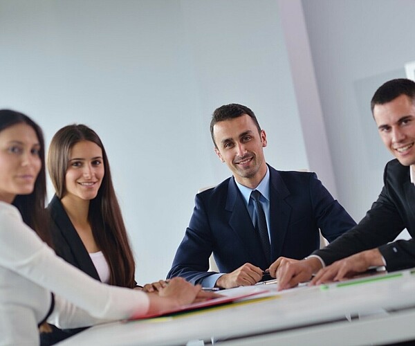 Gruppe von Büroarbeitern lächelt während eines Meetings in die Kamera