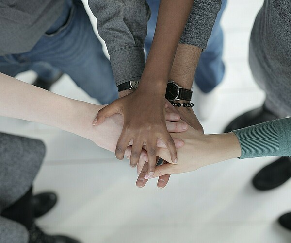 Gruppe mit unterschiedlichsten Hautfarben legt Hände aufeinander