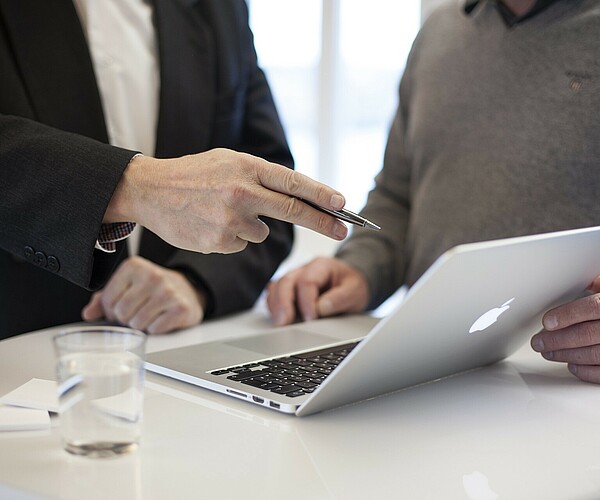 zwei Personen unterhalten sich während sie auf ein Laptop schauen