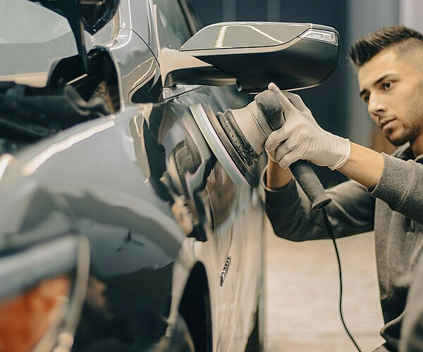 Mann lackiert die Tür eines Autos