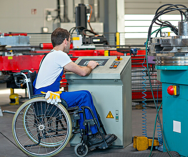 disabled worker in wheelchair in factory and his colleague