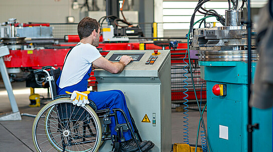 disabled worker in wheelchair in factory and his colleague