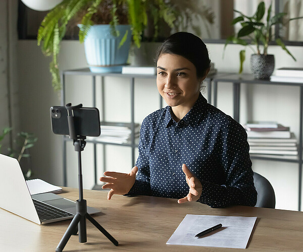 Successful Indian businesswoman recording webinar, using smartphone on tripod