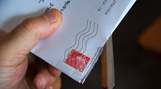 Brief mit Briefmarke wird geöffnet mit Brieföffner