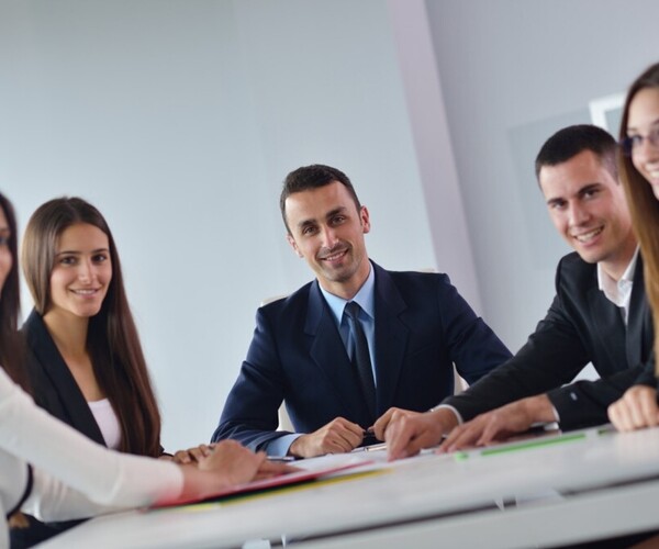 Gruppe von Büroarbeitern lächelt während eines Meetings in die Kamera