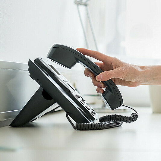 Person nimmt Telefonhörer ab