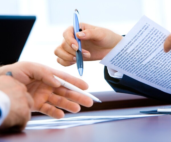 Hände halten Stifte und Blatt mit Text