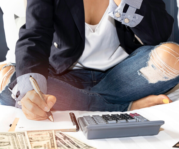 Selective focus of woman hand and calculator which she is a Budget planning and counting finance for paying taxes concept on the bed  Frau zählt Geld mit Taschenrechner