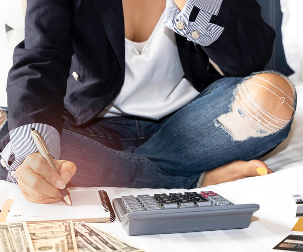 Selective focus of woman hand and calculator which she is a Budget planning and counting finance for paying taxes concept on the bed  Frau zählt Geld mit Taschenrechner