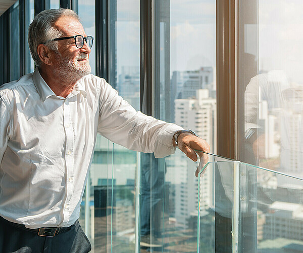 älterer Businessmann schaut aus dem Büro auf die Stadt