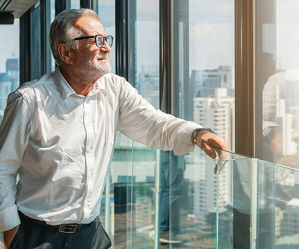 älterer Businessmann schaut aus dem Büro auf die Stadt