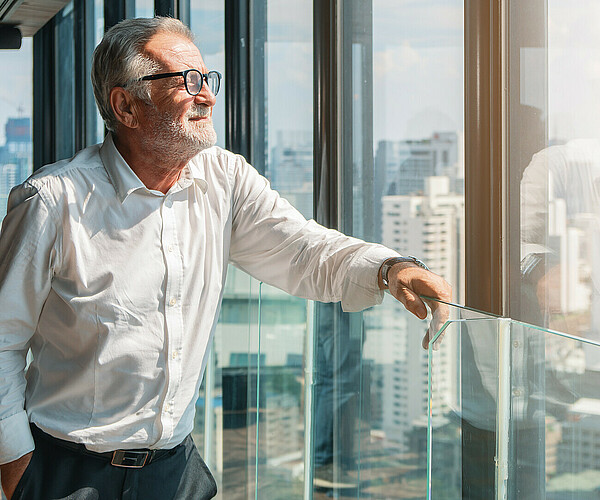 älterer Businessmann schaut aus dem Büro auf die Stadt