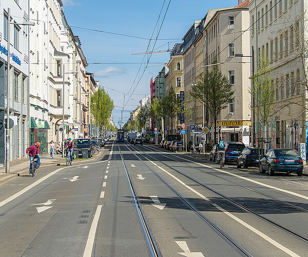 Eisenbahnstraße in Leipzig mit Straßenbahnschienen, parkenden Autos, Fahrradfahrern und Fußgängern