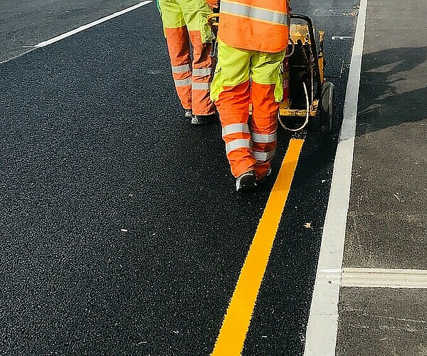 Arbeiter zeichnen Straßenbegrenzung für Bauarbeiten