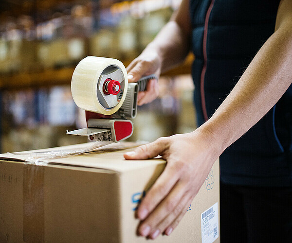 Male warehouse worker sealing cardboard boxes.