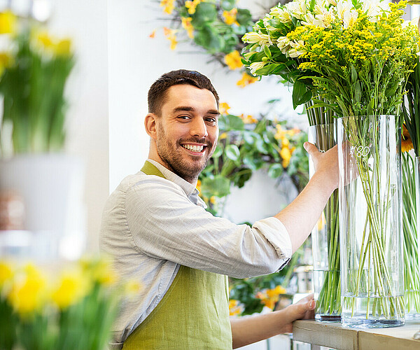 happy florist man setting flowers at flower shop