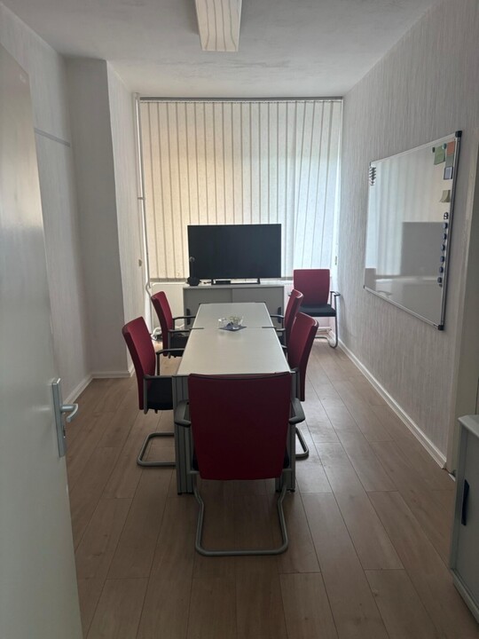 kleiner Konferenzraum mit Tisch, Stühlen, Monitor