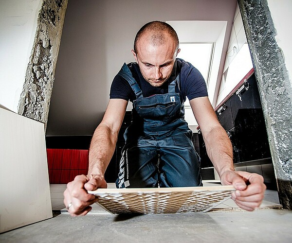 Fließenleger kniet während der Arbeit auf dem Boden