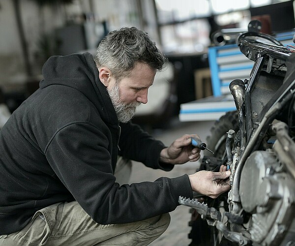 Mann schraubt an einem Motorrad herum