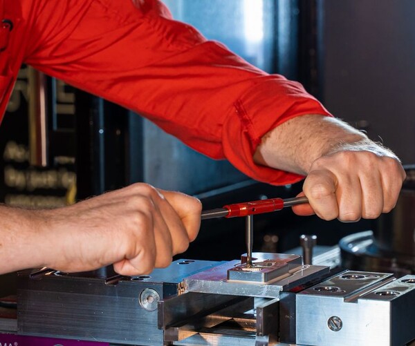 Arme und Hände eines Mannes, der an einer Maschine für Metallbearbeitung arbeitet
