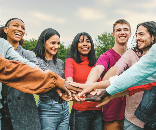 joyful team of multi-ethnic young people joining hands together - people diversity culture concept