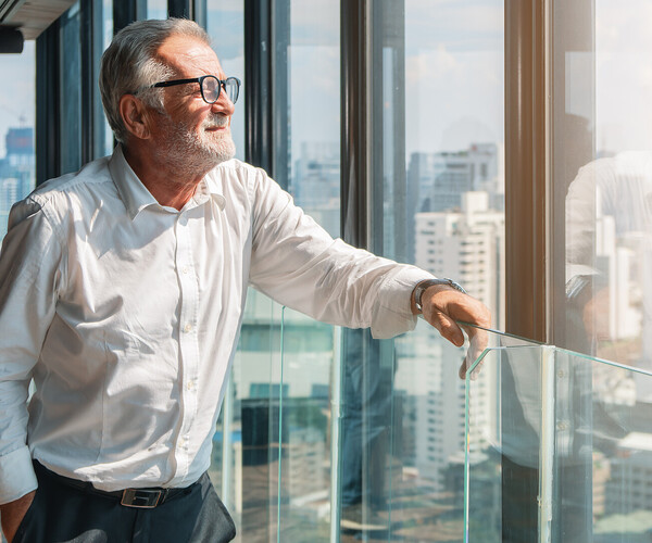 älterer Businessmann schaut aus dem Büro auf die Stadt