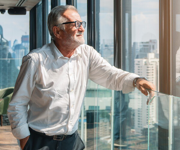 älterer Businessmann schaut aus dem Büro auf die Stadt