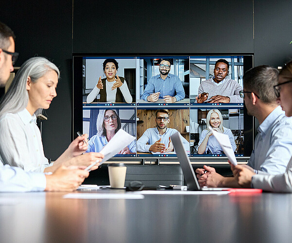 Global corporate video call in meeting room with diverse multiethnic people.