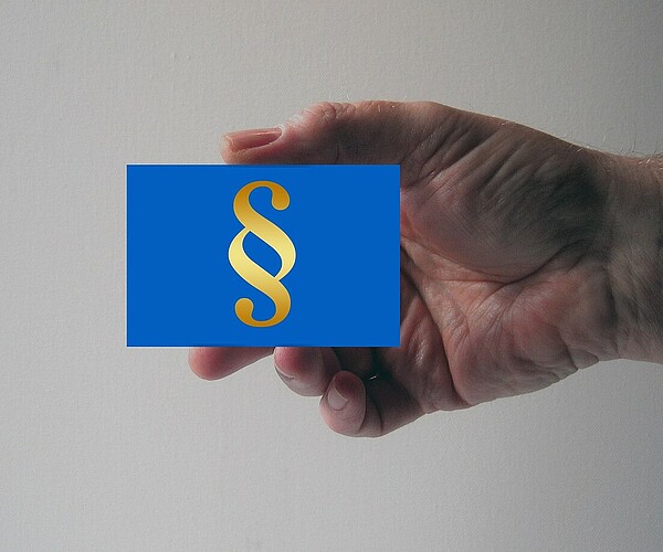 Hand hält Kärtchen mit Paragrafen-Symbol