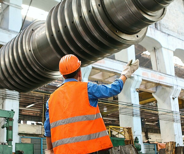 Anlagenmechaniker betrachtet großes, hängendes Metallteil