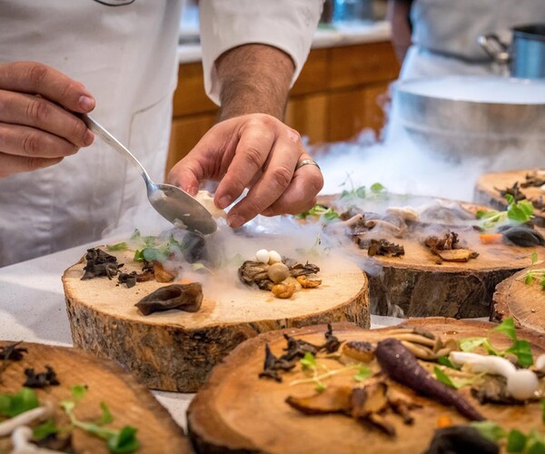 Ein Koch richtet Speisen auf einem Holzteller an