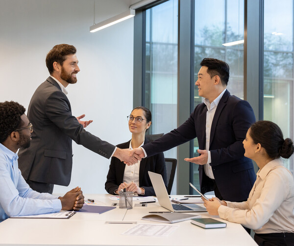 Professional business meeting in modern office with handshake and teamwork