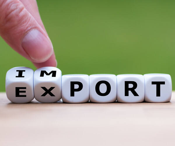 Ein Finger verschiebt Buchstabenwürfel, sodass die Wörter "Import" und "Export" gleichzeitig lesbar sind.