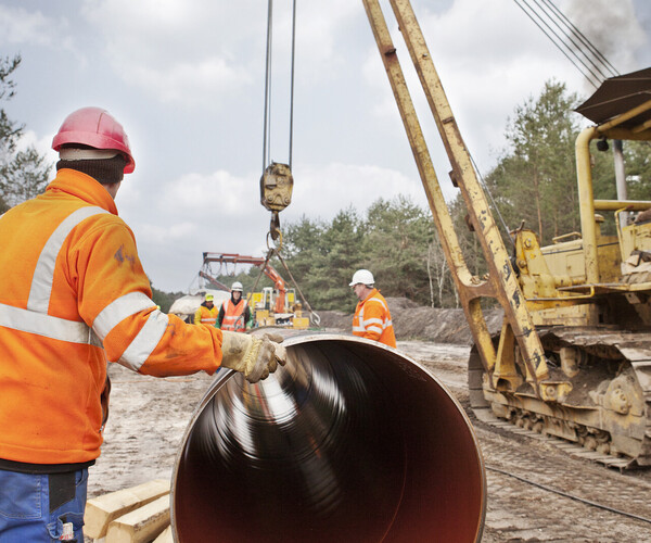 Bauarbeiter montieren mithilfe eines Krans eine Wasserstoffpipeline
