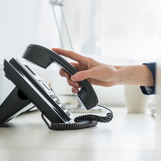 Person nimmt Telefonhörer ab