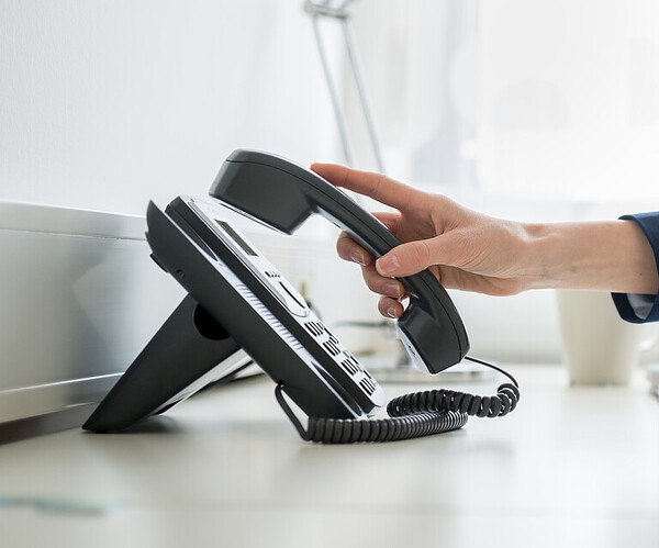 Person nimmt Telefonhörer ab